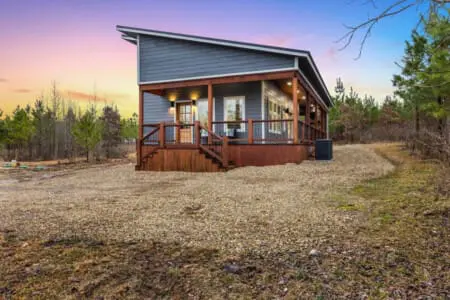 This modern cabin sits perfectly nestled in the pines with that wraparound porch that's basically begging you to slow down and actually be present for once.