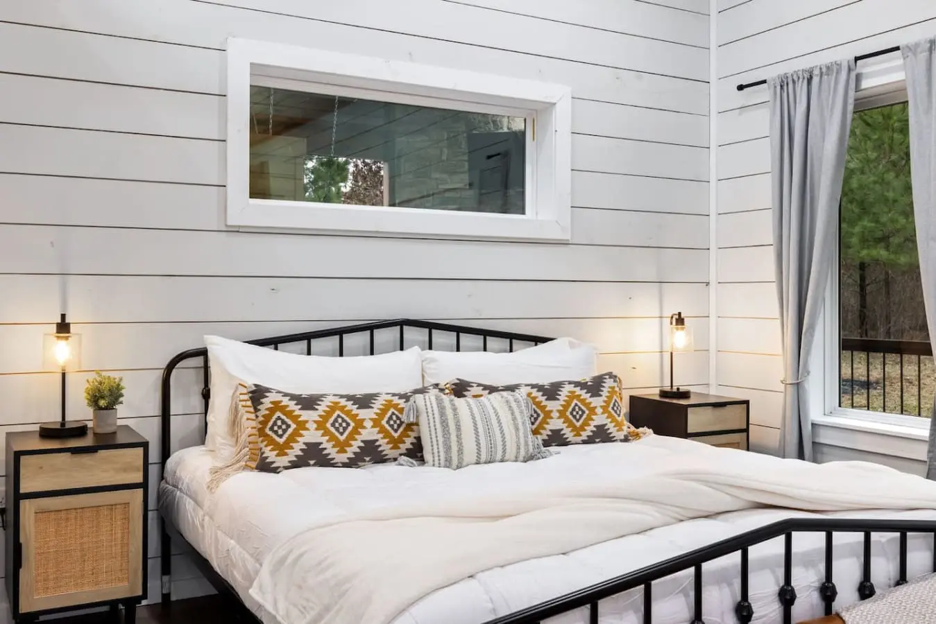 Wake up to forest views framed by that perfect horizontal window, snuggle under those mustard and charcoal patterned blankets, and realize this bedroom is basically the cozy, modern cabin aesthetic you've been dreaming about.