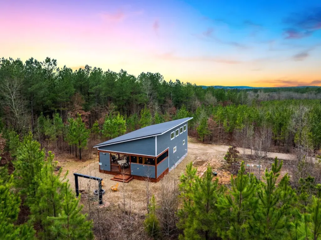 Tucked into a sprawling forest with nothing but trees and sky surrounding you, this modern cabin is basically your own private world where the sunset does the heavy lifting on the whole escape vibe.