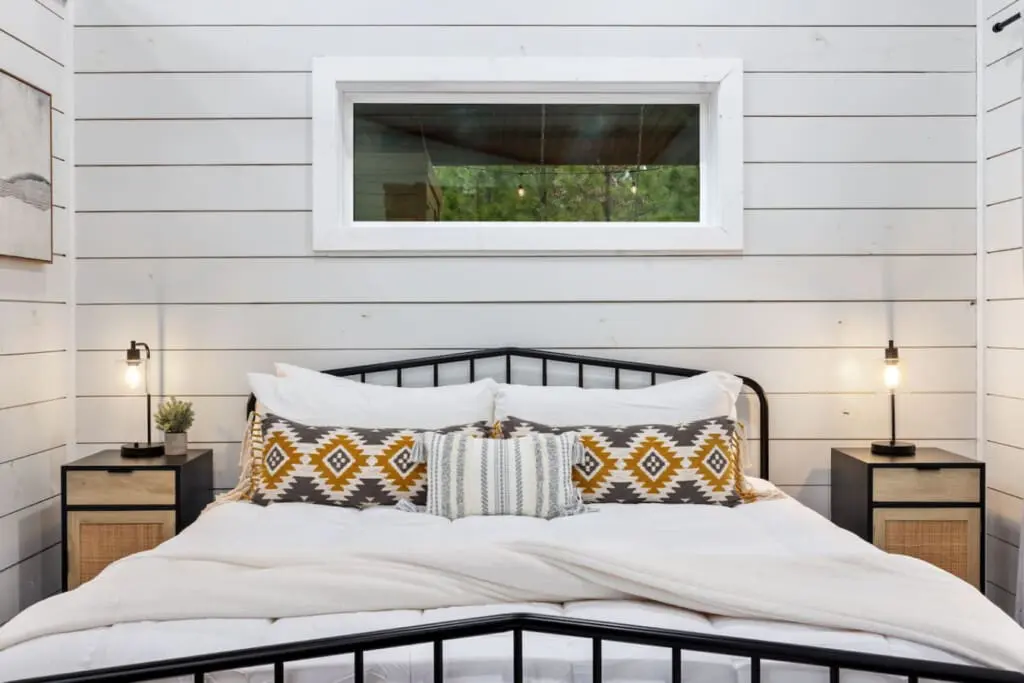Sink into this perfectly styled bed with those geometric throw pillows, gaze up at the forest through that tranquil window, and feel like you've stepped into that cozy cabin dream you didn't know you needed.