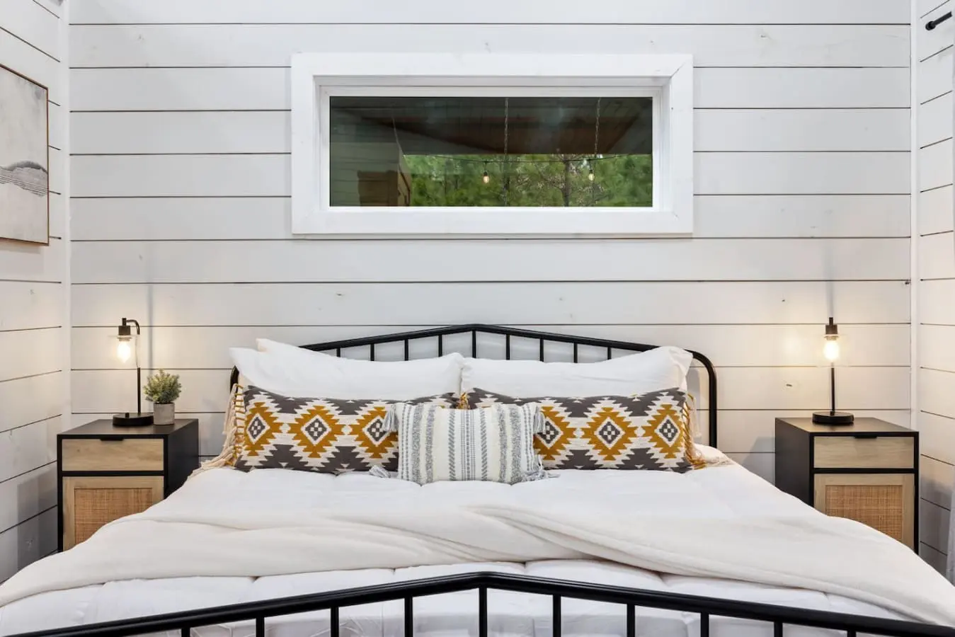 Sink into this perfectly styled bed with those geometric throw pillows, gaze up at the forest through that tranquil window, and feel like you've stepped into that cozy cabin dream you didn't know you needed.