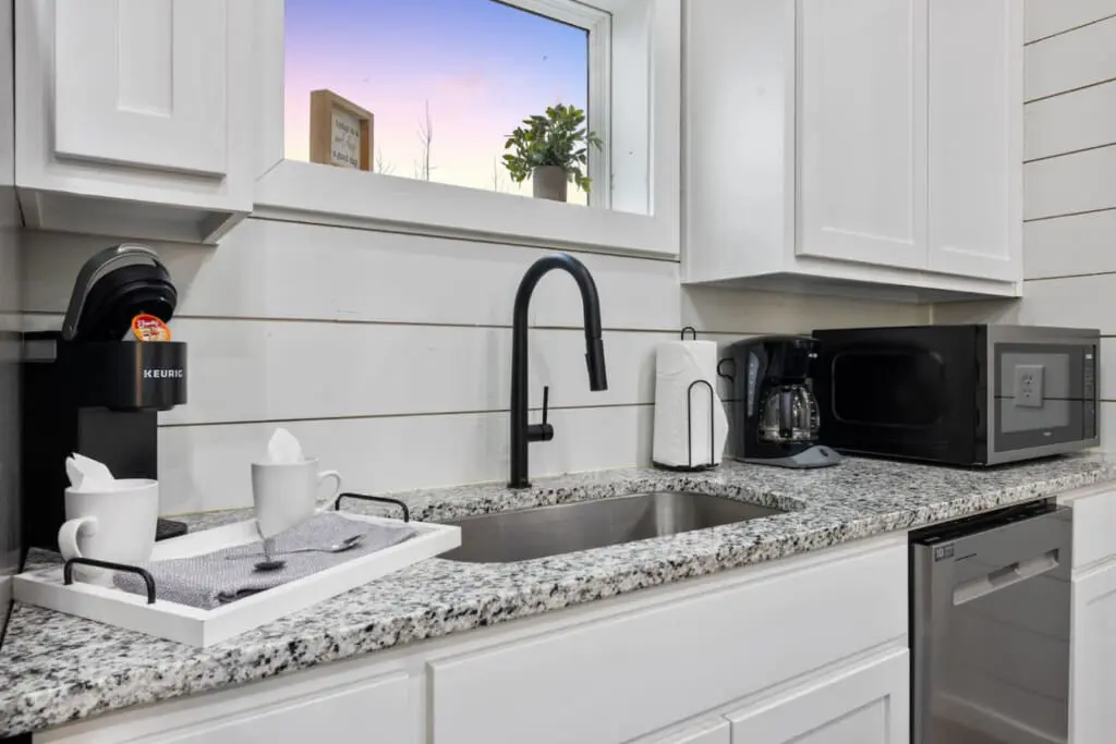 The kitchen's basically designed so you can actually cook something decent while staying completely connected to everyone hanging out in the living room—no disappearing into some separate space, just good vibes and granite countertops for days.