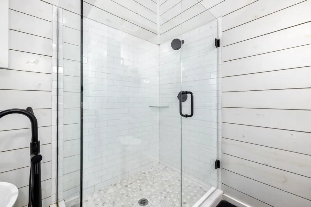 The walk-in shower with its crisp subway tile, rainfall showerhead, and river-rock floor is basically a spa moment waiting to happen every single time you need to rinse off the forest air.