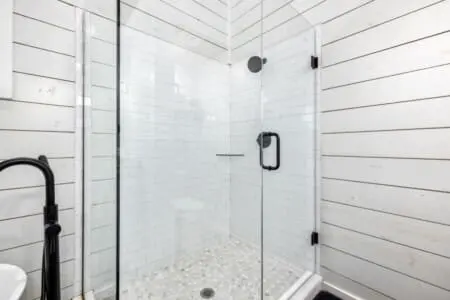 The walk-in shower with its crisp subway tile, rainfall showerhead, and river-rock floor is basically a spa moment waiting to happen every single time you need to rinse off the forest air.