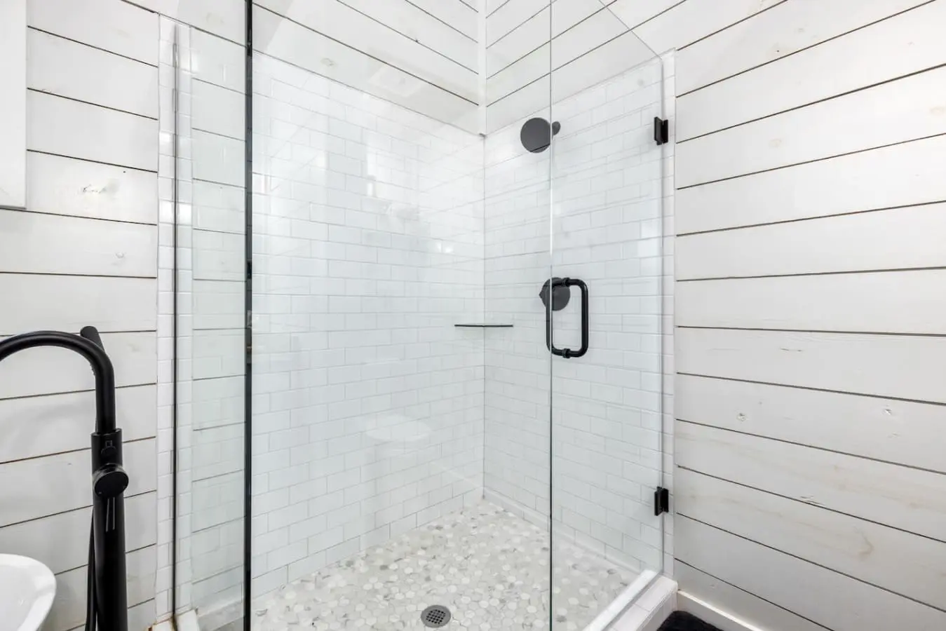 The walk-in shower with its crisp subway tile, rainfall showerhead, and river-rock floor is basically a spa moment waiting to happen every single time you need to rinse off the forest air.