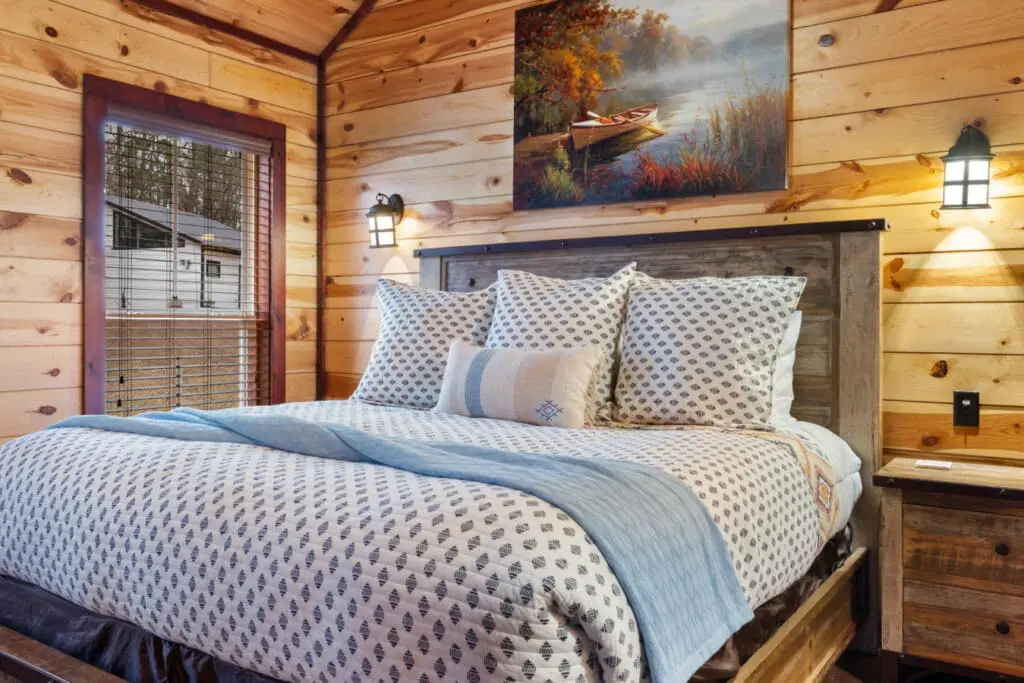 The bed is decorated with patterned throw pillows and a blue runner.