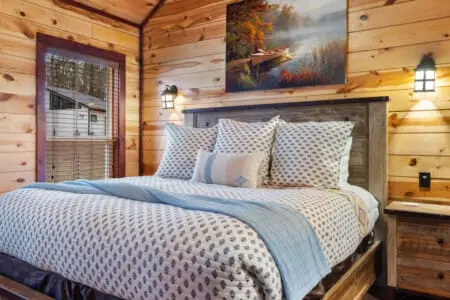 The bed is decorated with patterned throw pillows and a blue runner.