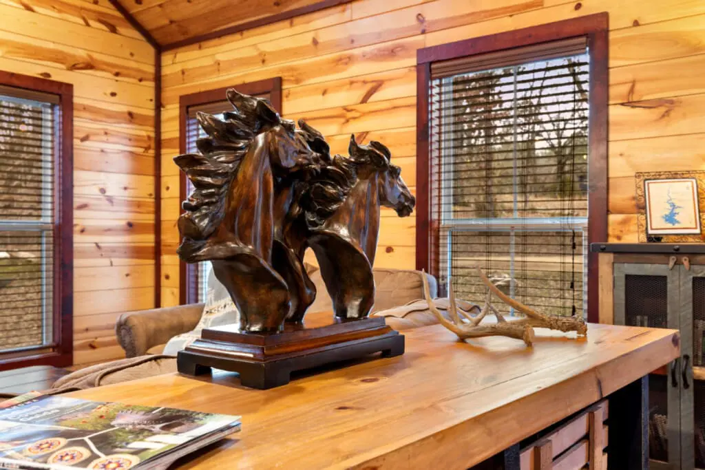 A cozy cabin interior featuring a striking wooden horse sculpture, antlers, and natural wood finishes, offering a peaceful escape.