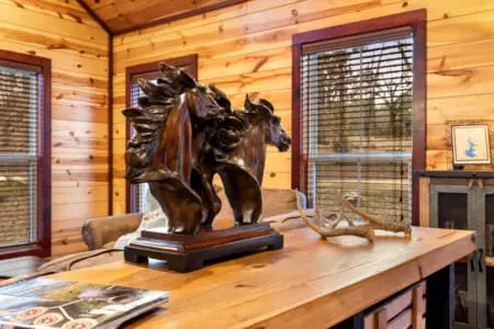 A cozy cabin interior featuring a striking wooden horse sculpture, antlers, and natural wood finishes, offering a peaceful escape.