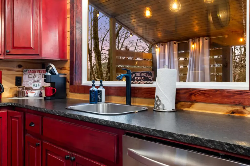 Red cabinets and a peaceful outdoor scene create the perfect cooking space.
