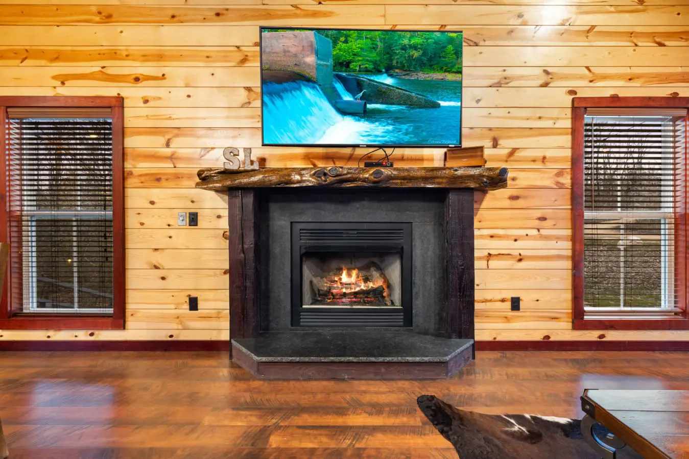 This cabin features a cozy fireplace with a rustic wooden mantel and a modern TV mounted above it.