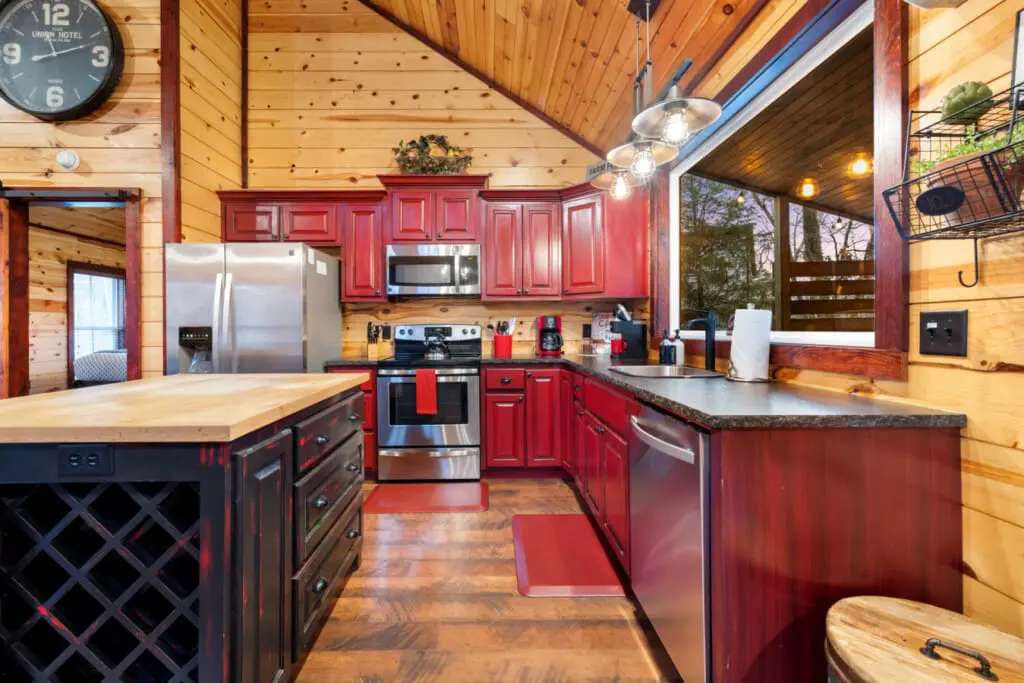 The kitchen features red cabinetry, a stainless steel refrigerator, and a modern microwave oven.