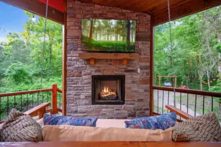 Curl up on the covered deck with a crackling fireplace, a flat-screen view of the forest, and swings within arm's reach—this is peak cozy cabin energy.