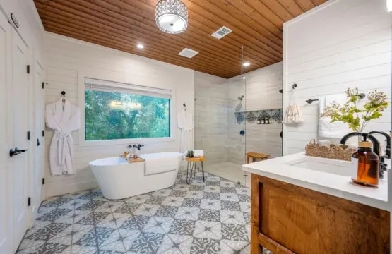 This primary bathroom is an absolute spa situation with that soaking tub by the window, a massive walk-in shower, and enough natural light and wood details to make you never want to leave.