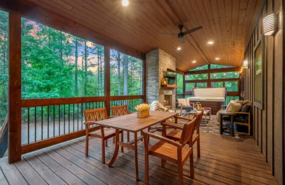 This covered deck is basically the ultimate hangout spot where you can eat at the table, lounge by the hot tub, pull up a chair by the fireplace, and somehow never run out of forest views to stare at.