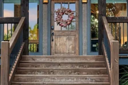 The moment you walk up these wooden steps and see that wreath hanging on the door with the forest peeking through those big windows, you just know this is going to be the kind of getaway where everything feels right.