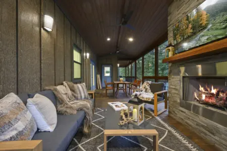 This screened porch with the fireplace glowing, cozy seating scattered around, and the forest literally wrapped around you on all sides basically feels like the ultimate argument for why you'd ever want to leave.