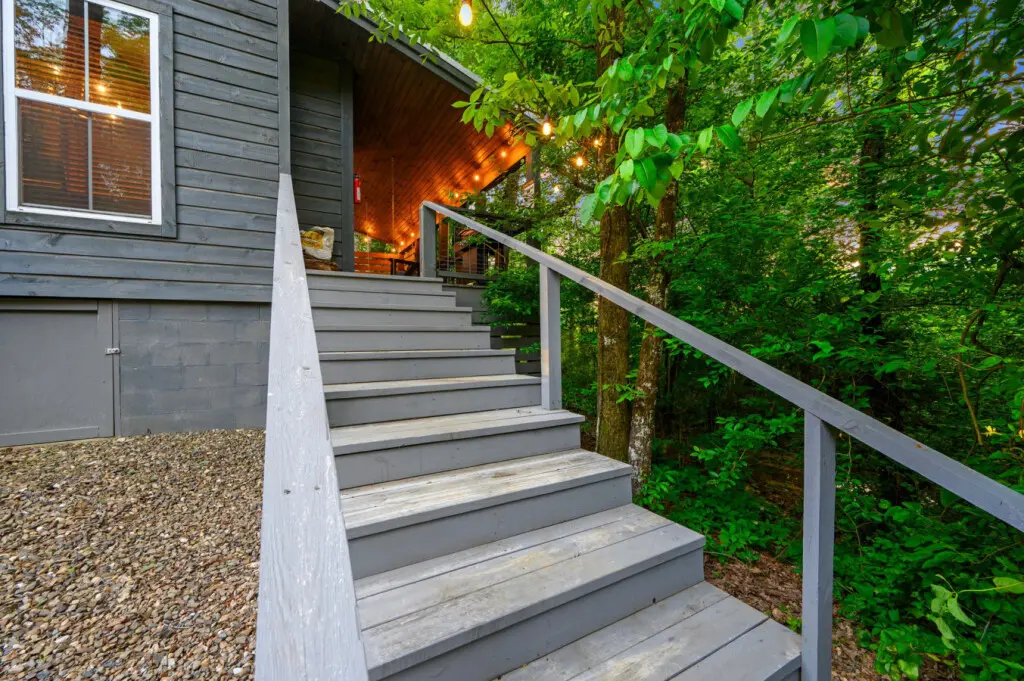 Grey wooden steps leading you up to a cozy cabin retreat tucked among the trees