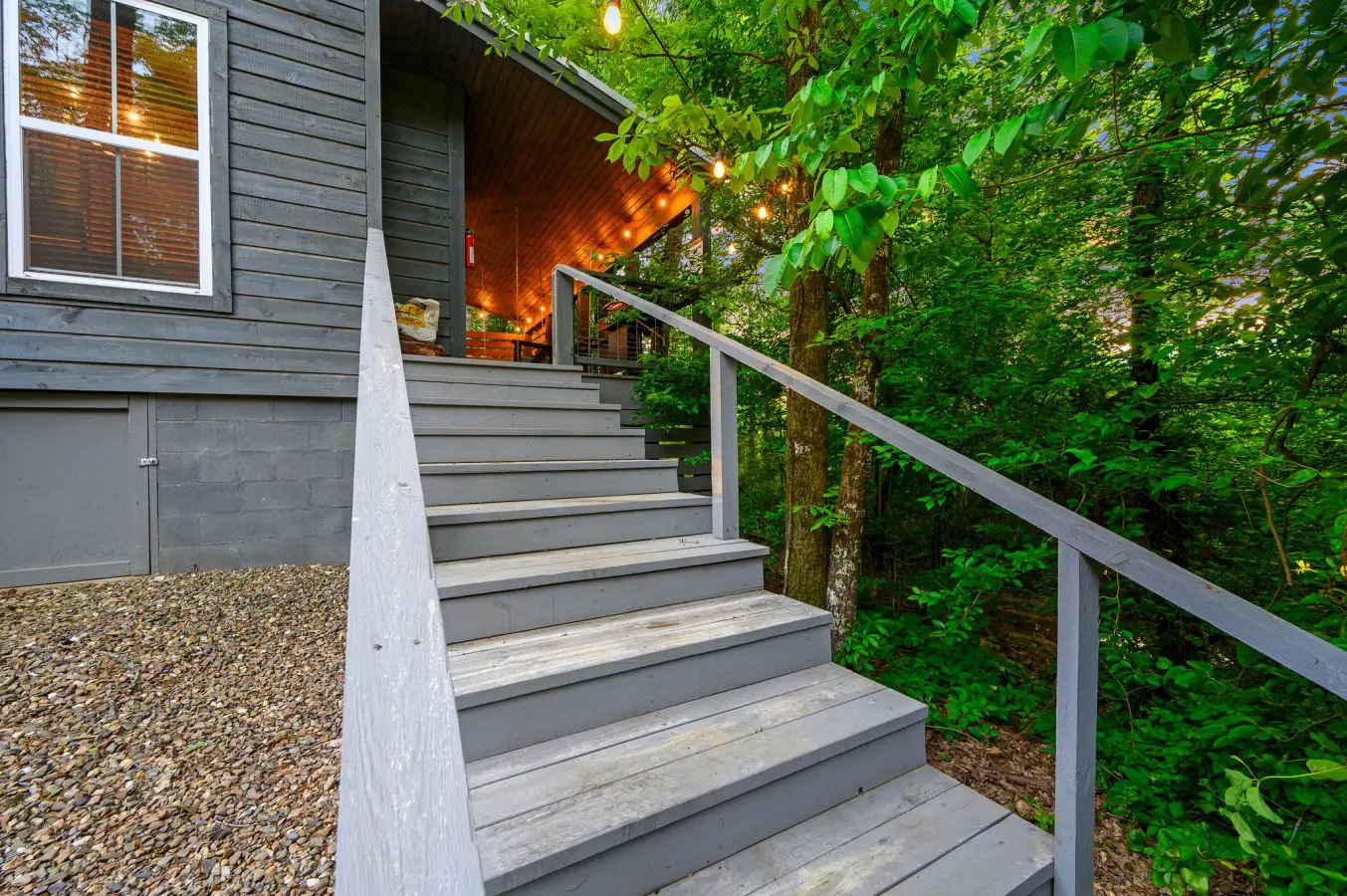 Grey wooden steps leading you up to a cozy cabin retreat tucked among the trees