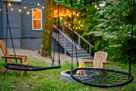Two circular net swings are suspended from trees, creating a relaxing seating area.