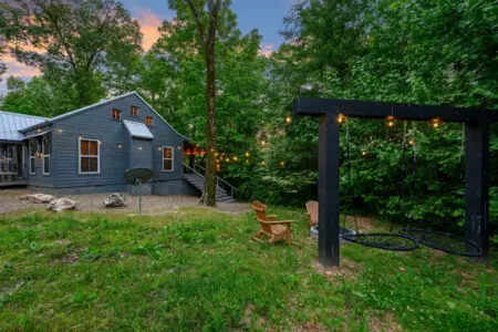 Side view of the property featuring a cozy firepit and warm string lights, creating the perfect setting for relaxing evenings outdoors