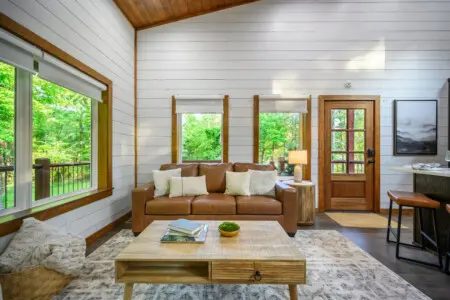 Sink into that buttery leather sofa with the whole forest as your backdrop, and you'll understand why this room feels less like a cabin interior and more like you're literally living inside a nature documentary.