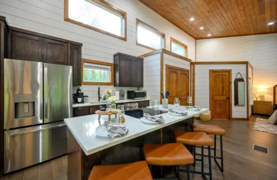 The kitchen's basically the heart of this place—high ceilings, stainless steel appliances, a massive island with those buttery leather stools, and enough counter space to actually cook something without feeling cramped.