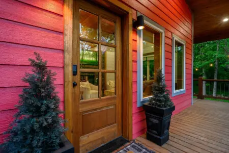 Step onto this porch at dusk and you'll understand why the front door is basically just a formality—this is where you're actually going to spend your time, watching the forest come alive while the cabin glows warm behind you.