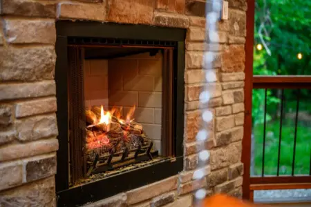Nothing beats watching flames dance and crackling wood pop while rain patters against those forest-view windows—this fireplace is basically the coziest corner of the whole place.