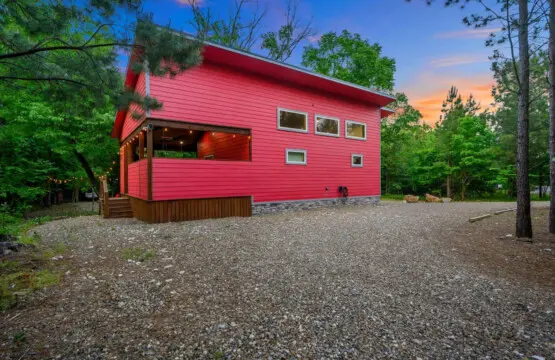 This bright red cabin tucked into the pines isn't just a place to stay—it's basically an invitation to step out of real life and into something way more fun.