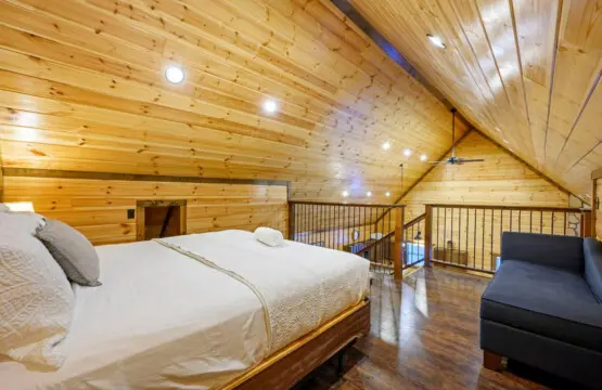 This spacious loft bedroom features soaring wood ceilings, recessed lighting, and a cozy loft seating area with views.