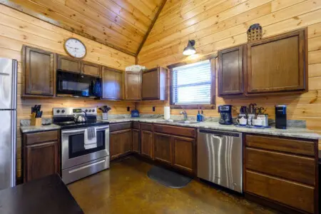 This spacious log cabin kitchen features stainless steel appliances, granite countertops, and plenty of storage for a comfortable stay.