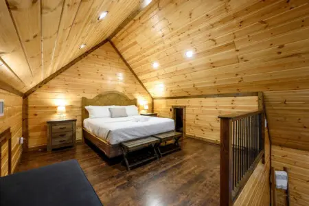 This cozy loft bedroom features soaring wood ceilings, a comfy king bed, and that perfect cabin retreat vibe.