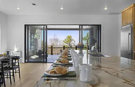 That marble island with views of the trees through the open doors — the kitchen earns its keep.