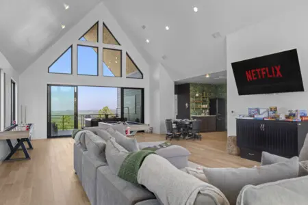 The game room has a pool table, foosball, a wall of board games, and those A-frame windows with views for days.