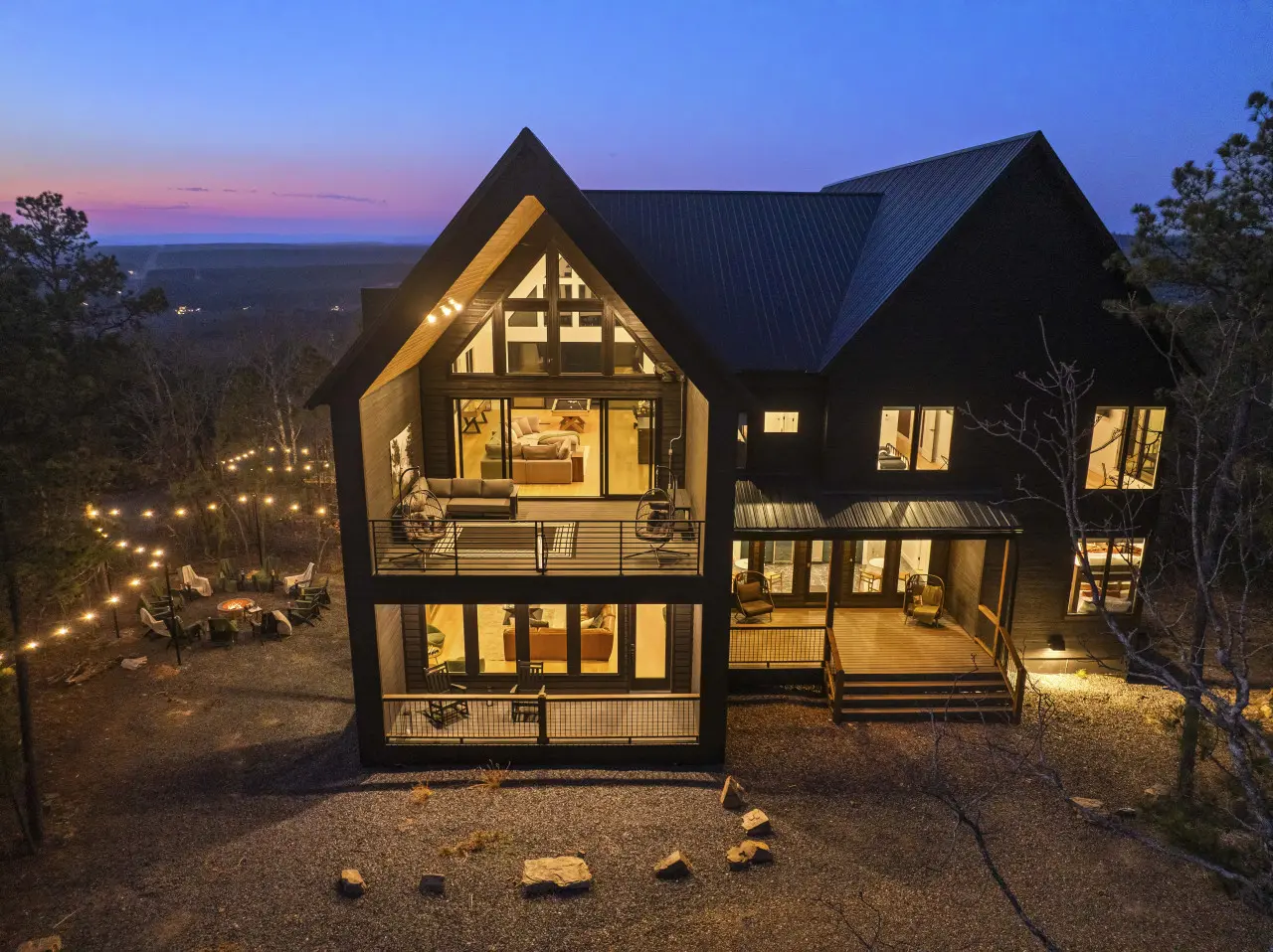That A-frame glow at dusk with the fire pit ready and string lights leading into the trees — Eagle's Vista does evenings right.