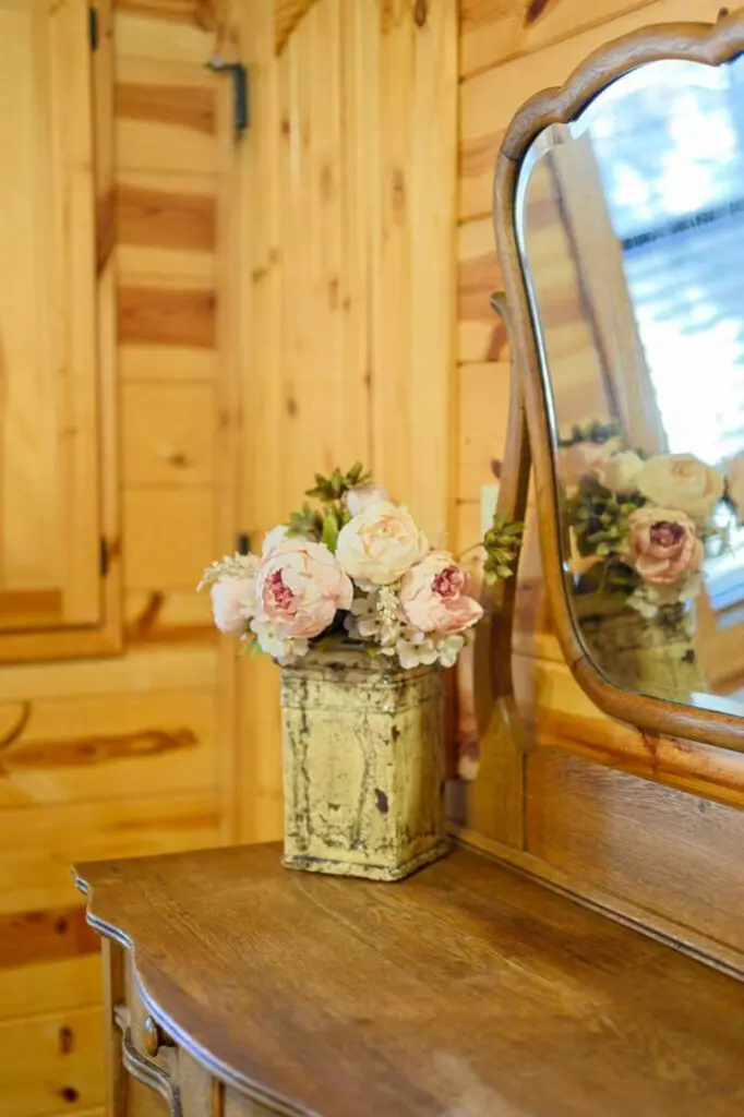 Beautiful natural wood cabin interior with charming vintage mirror and scenic water views through the window.
