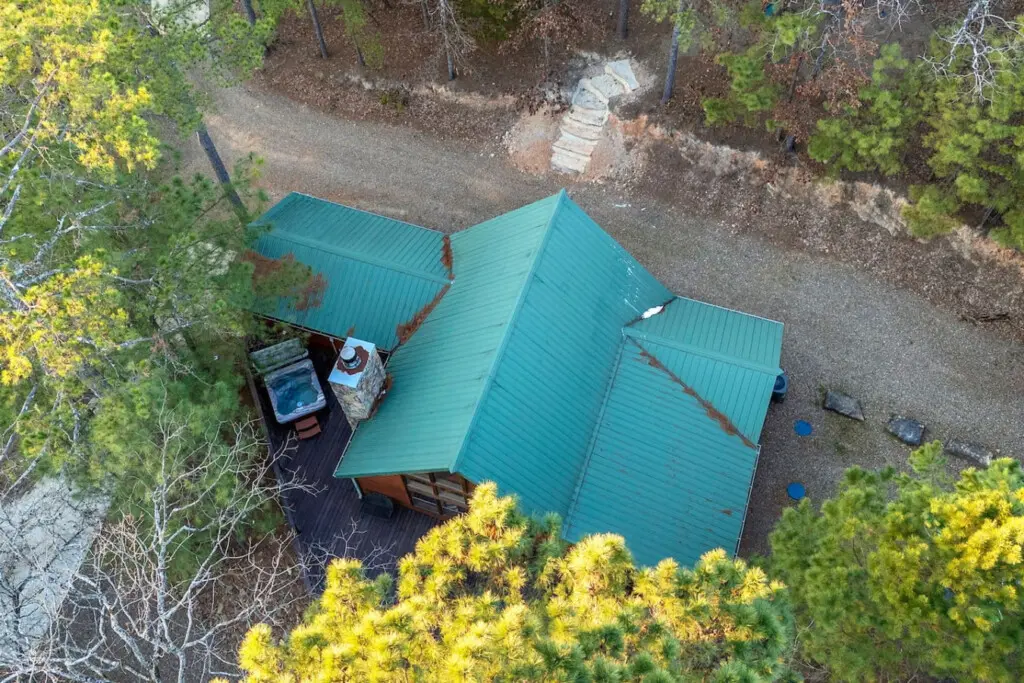 Cozy cabin nestled in the pines with a turquoise metal roof and peaceful forest surroundings.