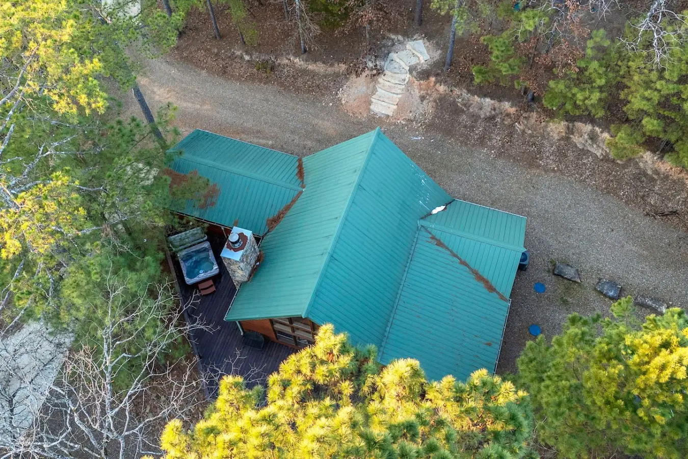 Cozy cabin nestled in the pines with a turquoise metal roof and peaceful forest surroundings.