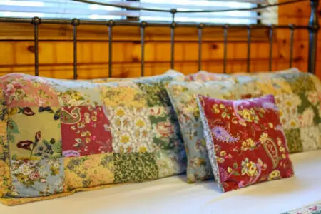 Cozy bedroom with a gorgeous wrought iron headboard and patchwork floral pillows that'll make you never want to leave.