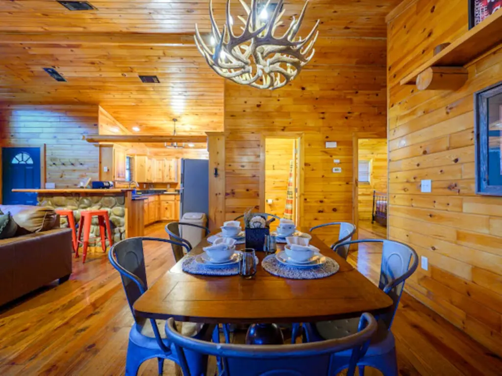 This cozy log cabin dining area flows seamlessly into the kitchen and living space with beautiful wood throughout.