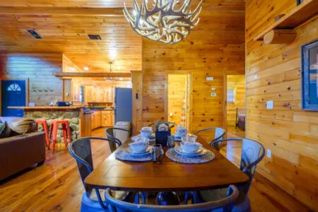 This cozy log cabin dining area flows seamlessly into the kitchen and living space with beautiful wood throughout.