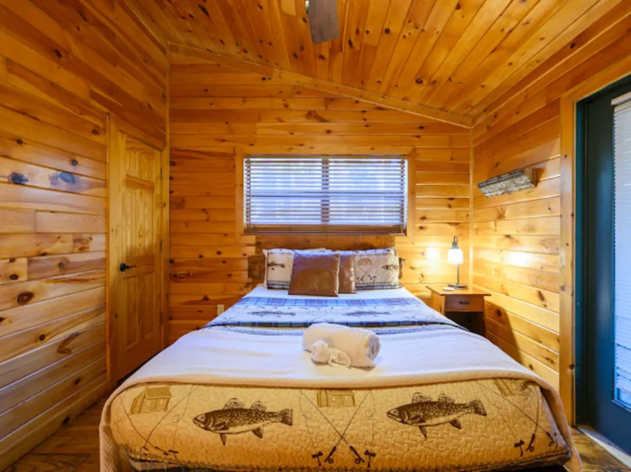 Cozy wood cabin bedroom with a queen bed, plenty of natural light, and that classic rustic lodge feel.