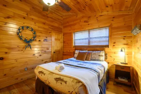 Cozy wood cabin bedroom with a queen bed, plenty of natural light, and rustic lodge charm throughout.