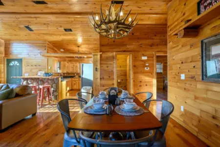 This cozy log cabin dining area flows seamlessly into the kitchen and living spaces with beautiful wood throughout.