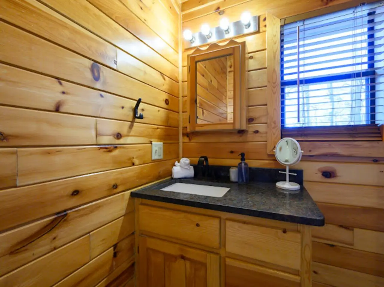 Cozy log cabin bathroom with slate countertop, modern vanity, and natural wood finishes throughout.