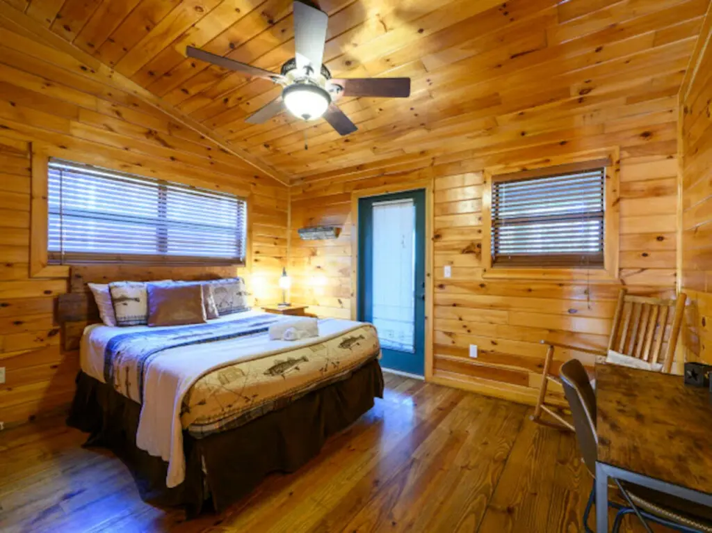 Cozy pine cabin bedroom with two windows, ceiling fan, and plenty of natural light for a peaceful retreat.