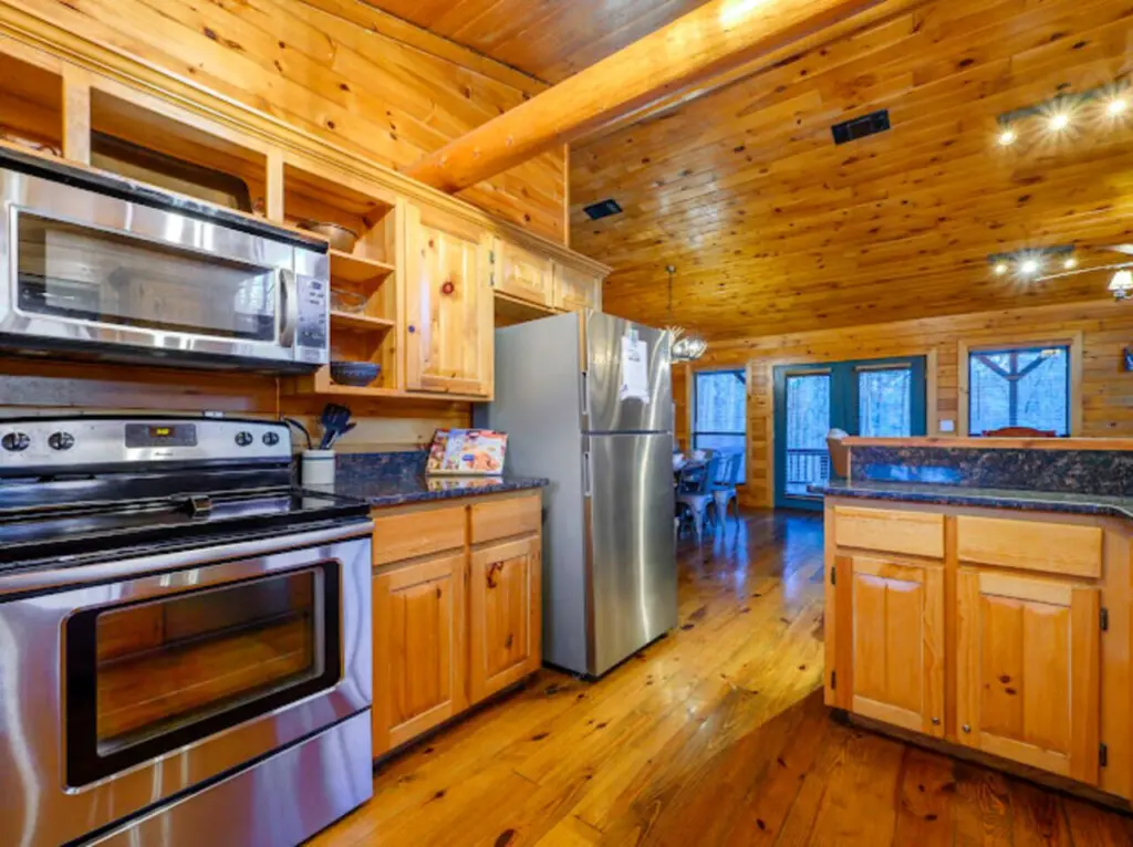 This gorgeous log cabin kitchen has stainless steel appliances and tons of windows overlooking the forest.