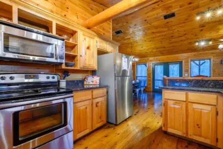 This gorgeous log cabin kitchen has stainless steel appliances and tons of windows overlooking the forest.