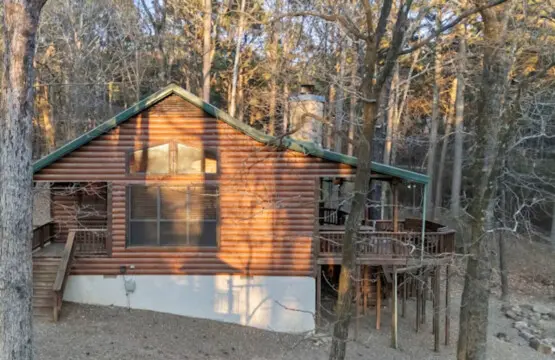 Cozy log cabin nestled among towering trees with plenty of deck space and natural light.